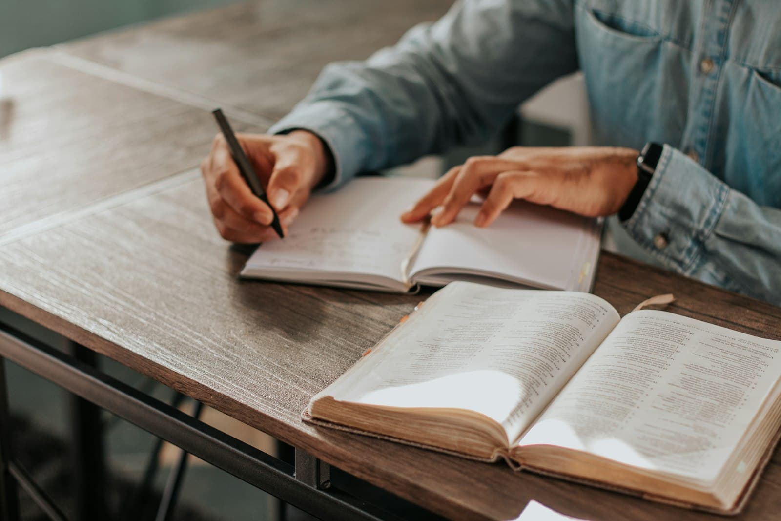 Writing plans in a notebook at a wooden desk